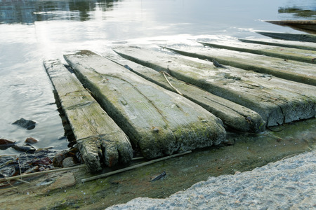 Wooden ramp used for putting boats into sea and the sky reflecting in the waterの写真素材