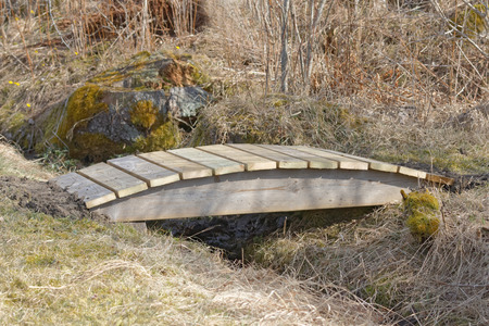 Small wooden curved bridge over the trench built of impregnated woodの写真素材