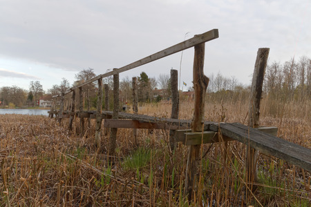 Long rickety wooden bridge used to reach the small lake through the flagの写真素材