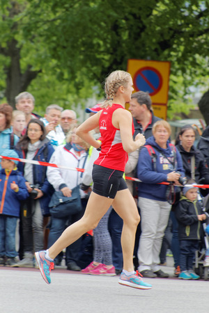 STOCKHOLM - MAY 30, 2015: Blond girl in red shirt running in the ASICS Stockholm Marathon event May 30, 2015 in Stockholm, Swedenのeditorial素材