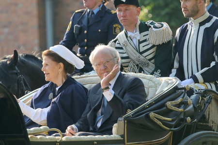 STOCKHOLM - JUN 06, 2015: The swedish king Carl XVI Gustaf waiving and the queen Silvia Bernadotte sitting in the royal horse wagon on their way to celebrate the swedish national dayのeditorial素材