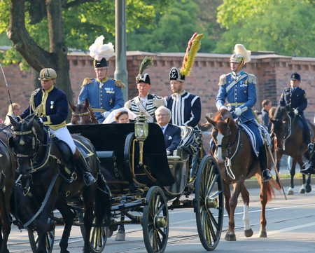 STOCKHOLM - JUN 06, 2015: The swedish king Carl XVI Gustaf and the queen Silvia Bernadotte sitting in the royal horse wagon on their way to celebrate the swedish national dayのeditorial素材