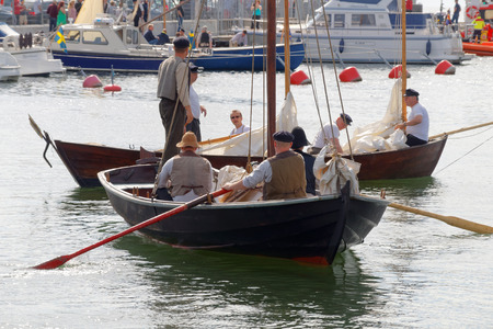 GRISSLEHAMN - JUN 13, 2015: Sailors in vintage clothes rowing old sailing ships in the harbor before the public event Postrodden, June 13, 2015 in Grisslehamn, Swedenのeditorial素材