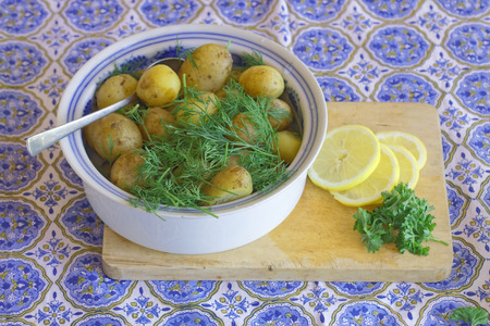 Swedish delicacy consisting of a bowl of potato, red onion and parsley on a table with a blue textured clothの写真素材