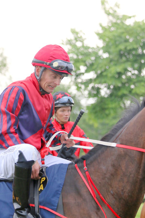 STOCKHOLM - JUNE 06: Two jockeys in red clothes sitting on their race horses at the Nationaldags Galoppen at Gardet. June 6, 2015 in Stockholmのeditorial素材