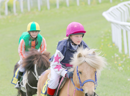 STOCKHOLM - JUNE 06: YYoung girl and young boy  sitting on ponys at the Nationaldags Galoppen at Gardet. June 6, 2015 in Stockholmのeditorial素材