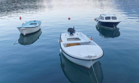 Thre small blue and white fishing boat in calm water in the first morning light