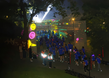 STOCKHOLM, SWEDEN - AUG 15, 2015: Group of runners in blue dresses running throgh a tunnel with a colorful laser show in the running event Midnattsloppet, August 15, 2015 in Stockholm, Swedenのeditorial素材