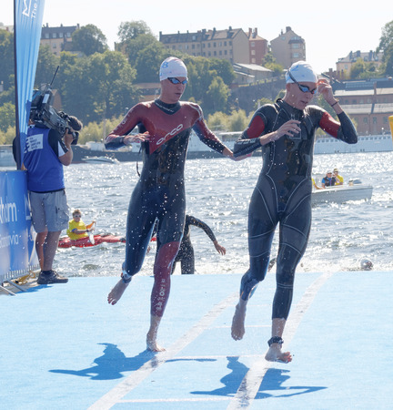 STOCKHOLM - AUG 22, 2015: Two female swimmer climbing up from the water in the Women's ITU World Triathlon series event August 22, 2015 in Stockholm, Swedenのeditorial素材
