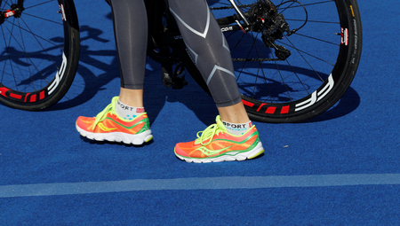 STOCKHOLM - AUG 22, 2015: Colorful shoes and legs of a triatlete and bicycle wheels in the Women's ITU World Triathlon series event August 22, 2015 in Stockholm, Swedenのeditorial素材