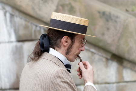 STOCKHOLM - SEPT 19, 2015: Elegant man wearing old fashioned trilby hat smoking a pipe in the Bike in Tweed event September 19, 2015 in Stockholm, Swedenのeditorial素材
