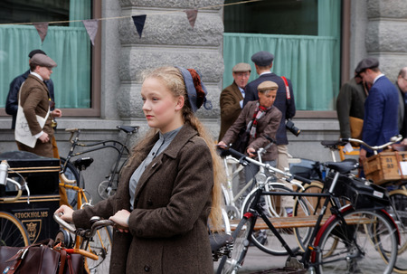 STOCKHOLM - SEPT 19, 2015: Young girl  wearing old fashioned tweed clothes leading her bicycle in the Bike in Tweed event September 19, 2015 in Stockholm, Swedenのeditorial素材