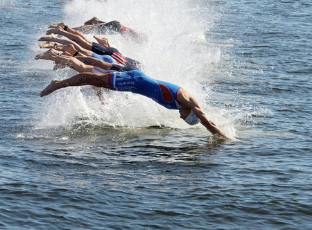 STOCKHOLM - AUG 22, 2015: Group of male swimming competitors in colorful swimsuits juming into the water when the start signal goes in the Mens's ITU World Triathlon series event August 22, 2015 in Stockholm, Swedenのeditorial素材