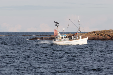 Small fishing boat used for cod fishing in front of an island in the swedish archipelagoの写真素材