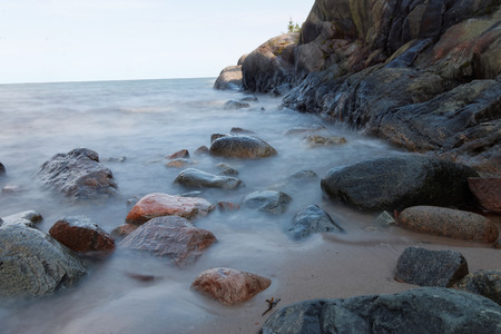 Mysterious milky water, stones, sand and a large rockの写真素材