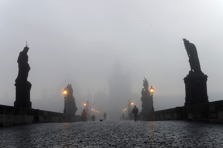 PRAGUE, CZECHOSLOVAKIA - DEC 07, 2015: Charles bridge in central Prague a foggy morning. Silhouette of church in the background and people walking. December 07, 2015 in Prague, Czechoslovakiaのeditorial素材