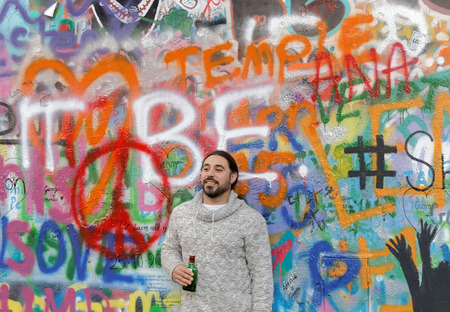 PRAGUE, CZECHIA - DEC 05, 2015: Man standing in front of the colorful public John Lennon Wall where there is a continous graffiti painting going on by tourists. December 05, 2015 in Prague, Czechiaのeditorial素材
