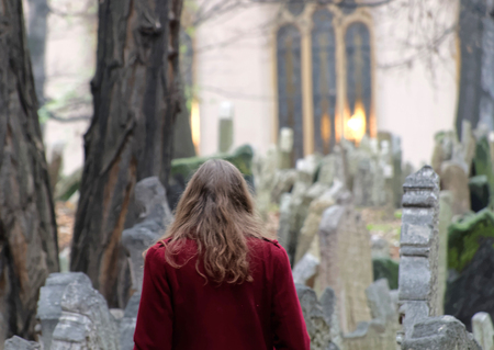 PRAGUE, CZECHIA - DEC 04, 2015: Old Jewish cemetery with lots of ancient headstones and a woman...