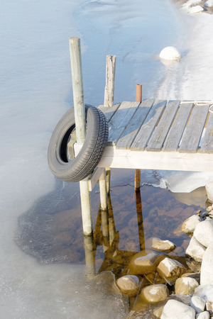 One small rural wooden bridge and melting ice a beautiful spring / winter day in the archipelagoの写真素材