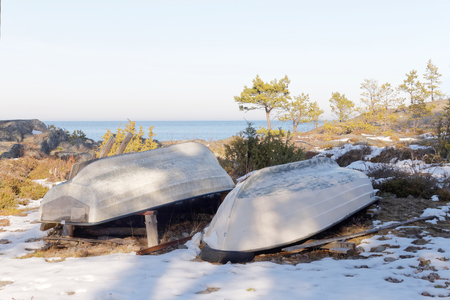 White row boats upside down on land waiting for the summer , the ocean in the backgroundの写真素材
