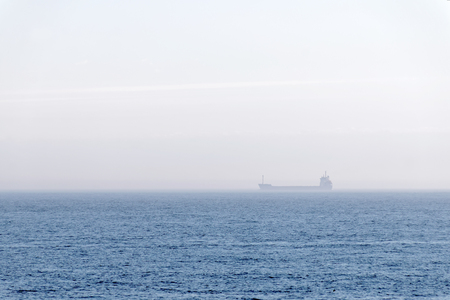 Large container ship partly hidden in fog, travveling at the Baltic sea a sunny day during spring time in scandinaviaの写真素材