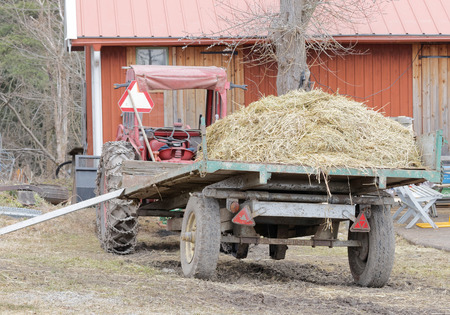 STOCKHOLM, SWEDEN - MAR 20, 2016: Old red tractor and a tractor trailer filled with hay at Oeverjarva Gard, Mars 20, 2016, Stockholm, Swedenのeditorial素材