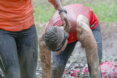 STOCKHOLM, SWEDEN - MAY 14, 2016: Man in red shirt covered with mud  bending forward in the forest...