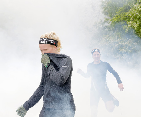 STOCKHOLM, SWEDEN - MAY 14, 2016: Blonde girl protecting her nose to the smoke in the obstacle race...