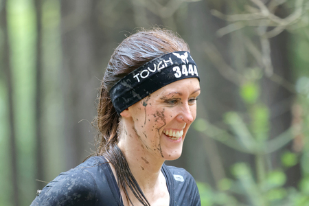 STOCKHOLM, SWEDEN - MAY 14, 2016: Smiling woman with mud in her face in the obstacle race Tough...