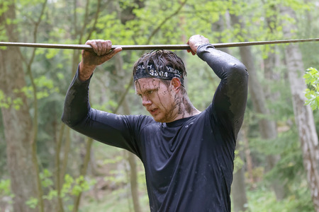 STOCKHOLM, SWEDEN - MAY 14, 2016: Concentrated man with mud in his face trying to maintain his balance on a slack rope in the obstacle race Tough Viking Event in Sweden, April 14, 2016のeditorial素材