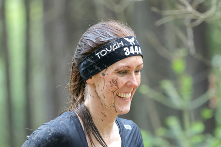 STOCKHOLM, SWEDEN - MAY 14, 2016: Smiling woman with mud in her face in the obstacle race Tough Viking Event in Sweden, April 14, 2016のeditorial素材