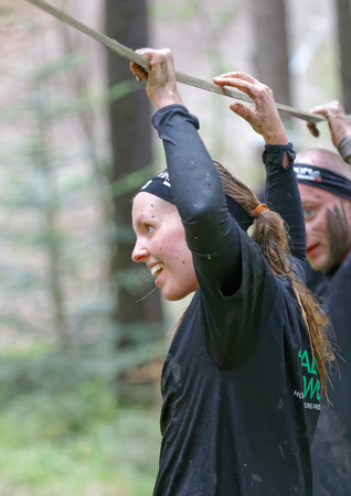 STOCKHOLM, SWEDEN - MAY 14, 2016: Smiling woman with mud in her face trying to maintain her balance on a slack rope in the obstacle race Tough Viking Event in Sweden, April 14, 2016のeditorial素材