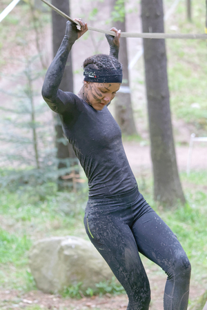 STOCKHOLM, SWEDEN - MAY 14, 2016: Woman with mud in her face trying to maintain her balance on a slack rope in the obstacle race Tough Viking Event in Sweden, April 14, 2016のeditorial素材