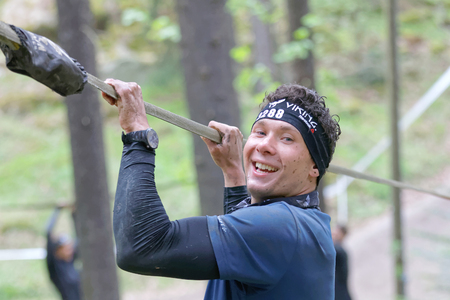 STOCKHOLM, SWEDEN - MAY 14, 2016: Smiling man trying to maintain his balance on a slack rope in the obstacle race Tough Viking Event in Sweden, April 14, 2016のeditorial素材