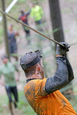 STOCKHOLM, SWEDEN - MAY 14, 2016: Rear viev of man with mud in his face trying to maintain his balance on a slack rope in the obstacle race Tough Viking Event in Sweden, April 14, 2016のeditorial素材