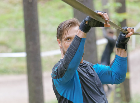 STOCKHOLM, SWEDEN - MAY 14, 2016: Man trying to maintain his balance on a slack rope in the obstacle race Tough Viking Event in Sweden, April 14, 2016のeditorial素材