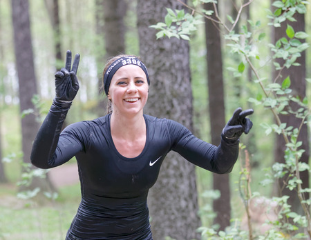 STOCKHOLM, SWEDEN - MAY 14, 2016: Smiling woman making victory sign in the obstacle race Tough Viking Event in Sweden, April 14, 2016のeditorial素材