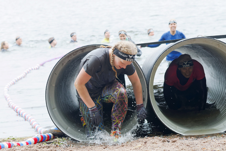 STOCKHOLM, SWEDEN - MAY 14, 2016: Woman coming out from a tube obstacle in the obstacle race Tough Viking Event in Sweden, May 14, 2016のeditorial素材