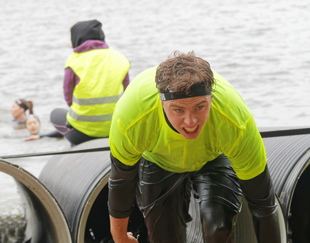 STOCKHOLM, SWEDEN - MAY 14, 2016: Man coming out from a tube obstacle in the obstacle race Tough Viking Event in Sweden, May 14, 2016のeditorial素材
