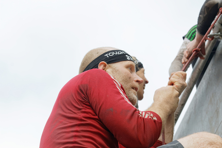 STOCKHOLM, SWEDEN - MAY 14, 2016: Man climbing the rampage obstacle, hanging in rope  in the obstacle race Tough Viking Event in Sweden, May 14, 2016のeditorial素材