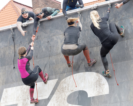 STOCKHOLM, SWEDEN - MAY 14, 2016: Three  woman climbing the rampage obstacle, hanging in rope and beeing helped in the obstacle race Tough Viking Event in Sweden, May 14, 2016のeditorial素材