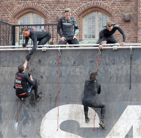 STOCKHOLM, SWEDEN - MAY 14, 2016: Group of men climbing the rampage obstacle, hanging in rope beeing...