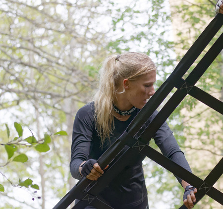 STOCKHOLM, SWEDEN - MAY 14, 2016: Blonde woman climbing a net obstacle in the obstacle race Tough Viking Event in Sweden, May 14, 2016のeditorial素材
