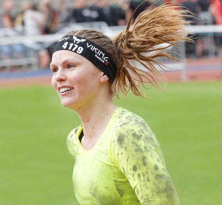 STOCKHOLM, SWEDEN - MAY 14, 2016: Happy smiling woman running and raising the hands in the obstacle race Tough Viking Event in Sweden, May 14, 2016のeditorial素材