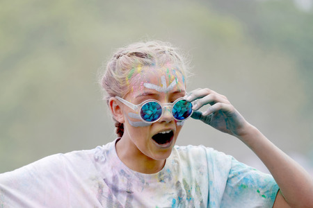 STOCKHOLM, SWEDEN - MAY 22, 2016: Young surprised woman wearing sunglasses covered with color powder...