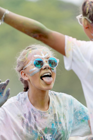 STOCKHOLM, SWEDEN - MAY 22, 2016: Young woman wearing sunglasses covered with color powder stick her tongue out in the Color Run Event in Sweden, May 22, 2016のeditorial素材