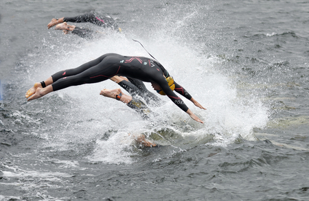STOCKHOLM - JUL 02, 2016: The female competitors wearing yellow bathing cap jump into the water after the start signal in the Women's ITU World Triathlon series event July 02, 2016 in Stockholm, Swedenのeditorial素材
