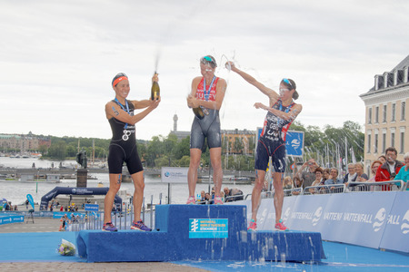 STOCKHOLM - JUL 02, 2016: Flora Duffy, Andrea Hewitt and Helen Jenkins laughing and squirting champagne on the winner's stand in the Women's ITU World Triathlon series event July 02, 2016 in Stockholm, Swedenのeditorial素材