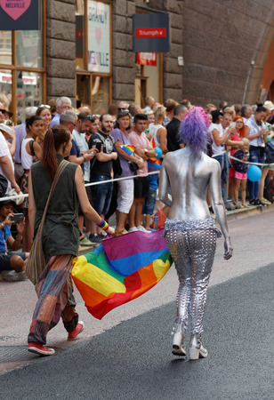 STOCKHOLM, SWEDEN - JUL 30, 2016: Two woman carrying the rainbow pride flag, one woman half naked covered with silver color in the Pride parade July 30, 2016 in Stockholm, Swedenのeditorial素材