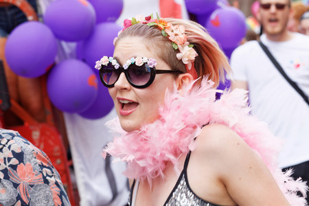 STOCKHOLM, SWEDEN - JUL 30, 2016: Smiling girl wearing glasses with flowers and feather boa in the Pride parade July 30, 2016 in Stockholm, Swedenのeditorial素材